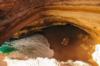 Portekiz 'deki ünlü Benagil plajında kayalar, sahilde dalgalar, vadi manzarası, öfkeli okyanus.