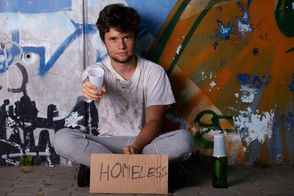 Un vagabundo pidiendo ayuda, sentado en una calle — Foto de Stock