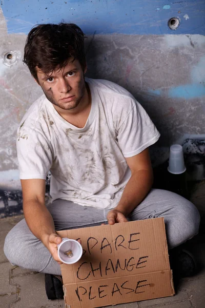 Tipo sin hogar pidiendo ayuda y cambio de repuesto, sentado en un brillo — Foto de Stock