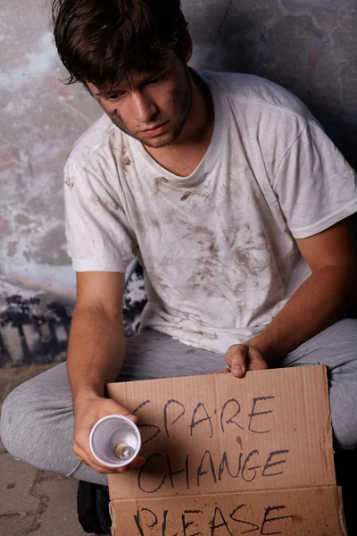 Tipo sin hogar pidiendo ayuda y cambio de repuesto, sentado en un brillo — Foto de Stock