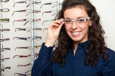 Young woman at optician with glasses, background in optician sho clipart