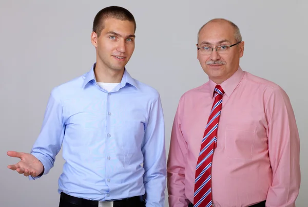 Senior businessman with junior businessman colleague, isolated o Stock Image