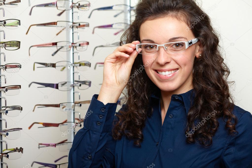 Young woman at optician with glasses, background in optician sho