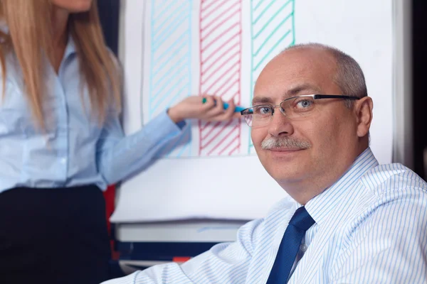 Junge Geschäftsfrau überreicht Graf an Senior-Geschäftsmann, Backgrou — Stockfoto