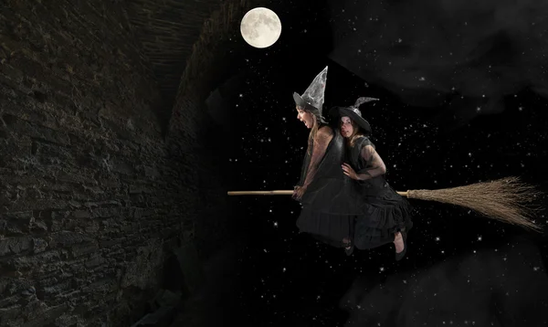 Two scared witches flying on a broom. Black background — Stock Photo, Image