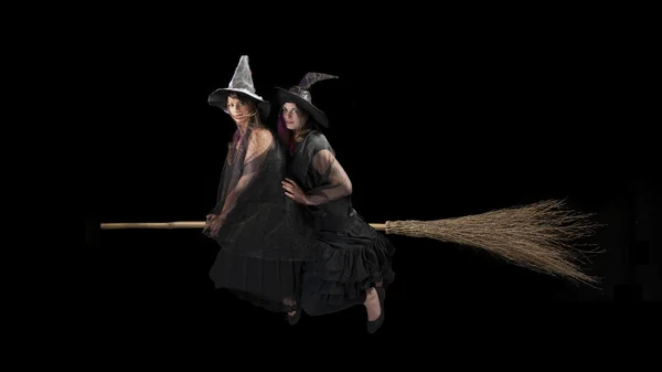 Two scared witches flying on a broom. Black background — Stock Photo, Image