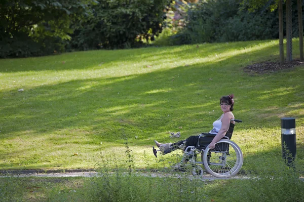 Adult woman in wheelchair outdoors in the park — Stock Photo, Image