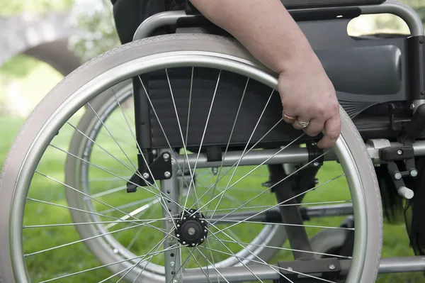 Primer plano en la mano y silla de ruedas — Foto de Stock