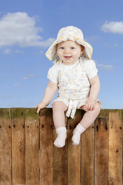 Baby sitting on a wooden fence — Stock Photo, Image