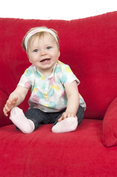 Bebé niña en un gran sofá rojo —  Fotos de Stock