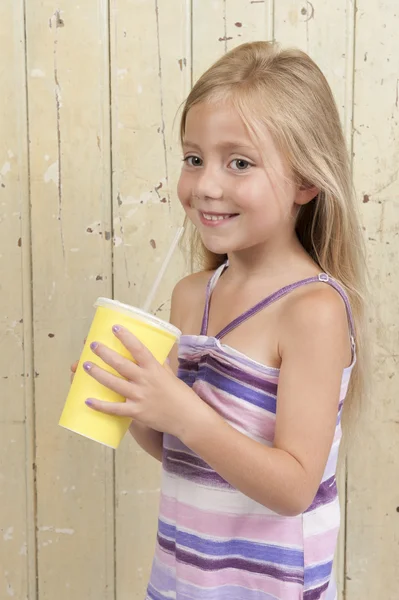 Chica bebiendo un refresco en una taza de cartón amarillo —  Fotos de Stock