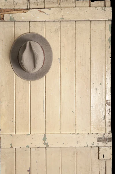 Leather cowboy hat hanging on an old door — Stock Photo, Image