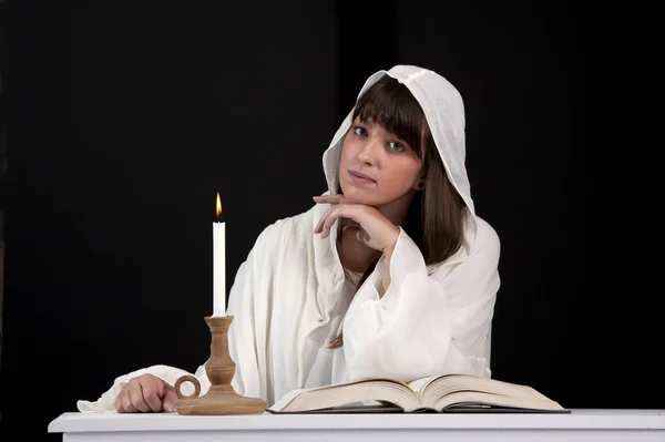 Femme de lecture en blanc, avec bougie — Photo