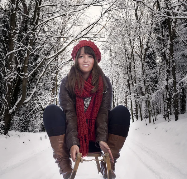 Jovem mulher fazendo um trenó deslizando em uma estrada de inverno — Fotografia de Stock