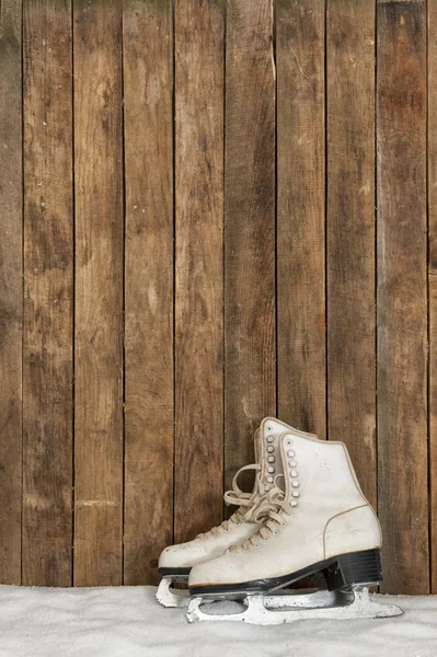 Old ice skates against an weathered wooden wall — Stock Photo, Image