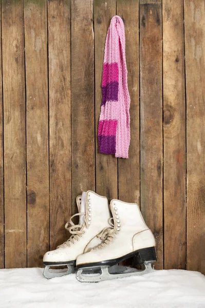 Vecchi pattini da ghiaccio e sciarpa contro una parete di legno intemperie — Foto Stock