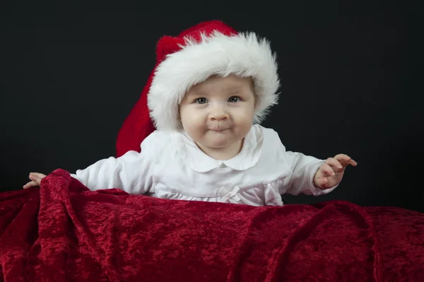 Baby mit Weihnachtsmütze auf dem Bauch liegend, — Stockfoto