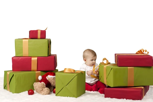 Baby seated between christmas presents, isolated on white — Stock Photo, Image