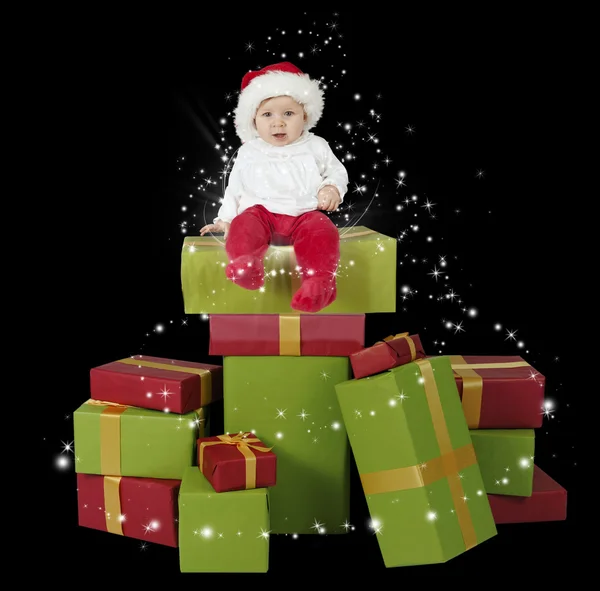 Baby sitzt auf einem Stapel Weihnachtsgeschenke, mit Sternen — Stockfoto