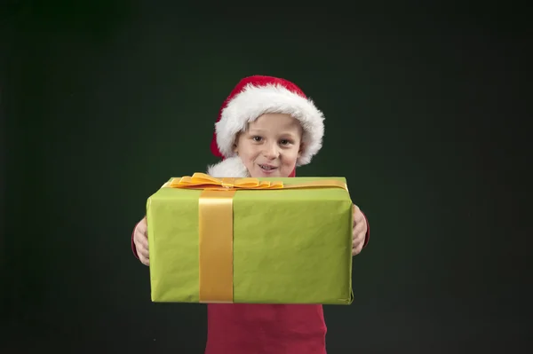 Boy with christmas hat and present on dark green — Stock Photo, Image