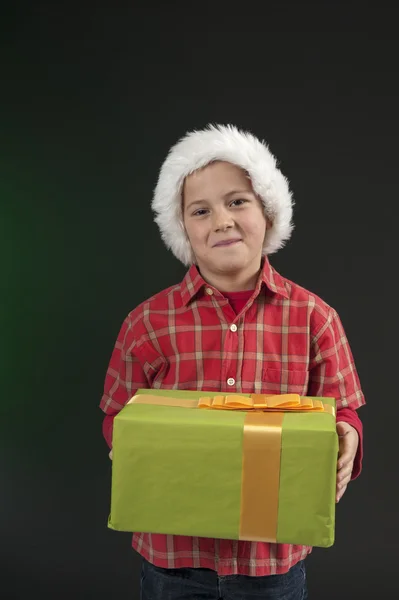 Pojke med jul hatt och närvarande på mörkgrön — Stockfoto
