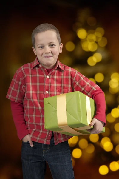 Menino com chapéu de Natal e presente na frente da árvore de xmas — Fotografia de Stock