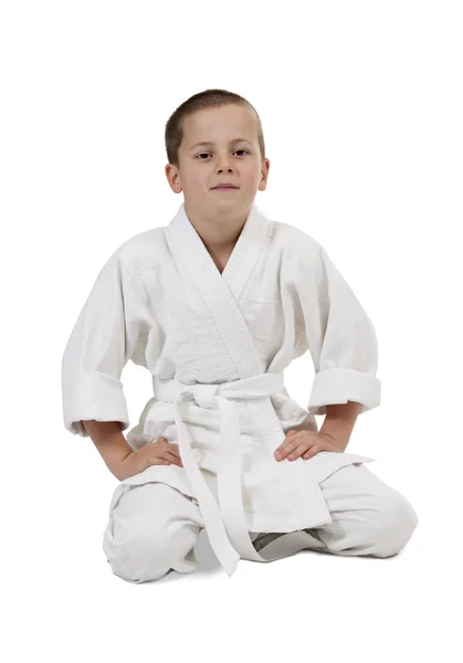 Сидячий хлопчик в дзюдо кімоно на білому — стокове фото