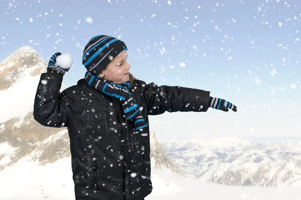 Pojke kastar en snöboll utomhus i bergen — Stockfoto