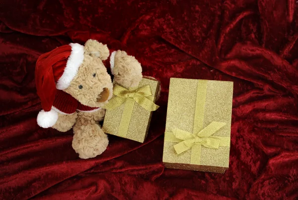 Ours en peluche avec boîte cadeau dorée sur rouge — Photo