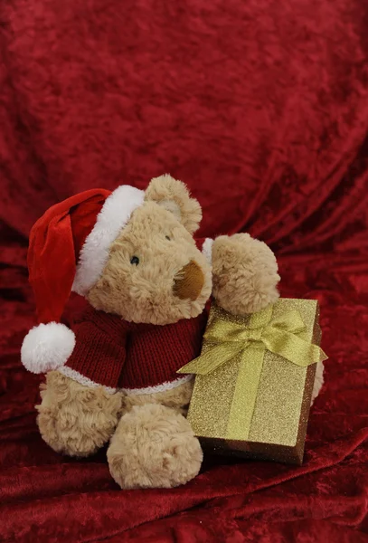 Nallebjörn med gyllene presentförpackning på röd — Stockfoto