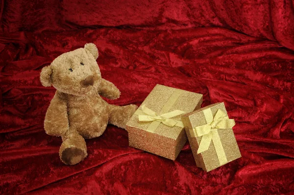 Teddybeer met golden cadeau doos op rood — Stockfoto