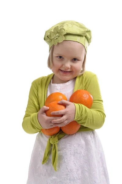 Маленькая девочка несет много апельсинов — стоковое фото