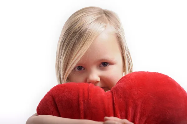 Little girl holding a heart shaped pillow — Stock Photo, Image