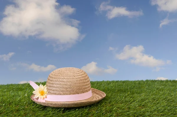 Slaměný klobouk s květem, ležící na trávě — Stock fotografie