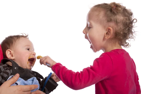 Menina alimentando seu irmão bebê — Fotografia de Stock