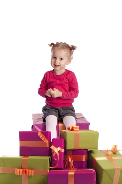 Kleines Mädchen sitzt zwischen vielen Geschenken — Stockfoto