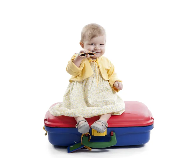 Little baby girl seated on a red and blue suitcas — Stock Photo, Image