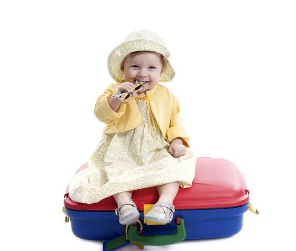 Little baby girl seated on a red and blue suitcas — Stock Photo, Image