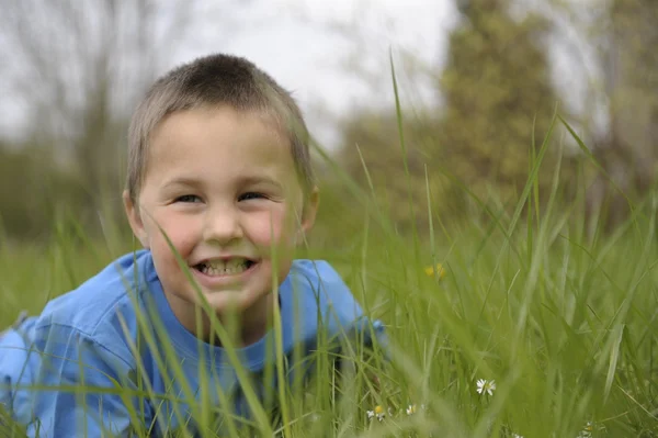 Kleiner Junge liegt auf dem Bauch im Gras — Stockfoto