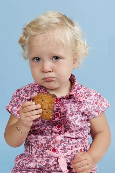 Little girl eating a biscuit. — Stock Photo, Image