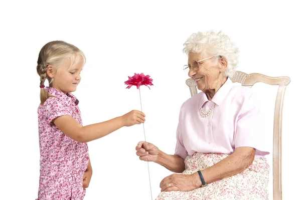 Liten flicka att ge henne bra mormor en blomma — Stockfoto