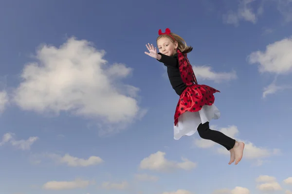 Liten flicka som en flygande lady bug, blå himmel med moln — Stockfoto