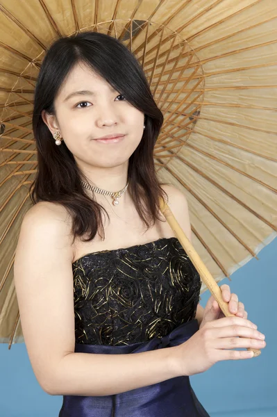 Young asian woman with umbrella, isolated on blue — Stock Photo, Image