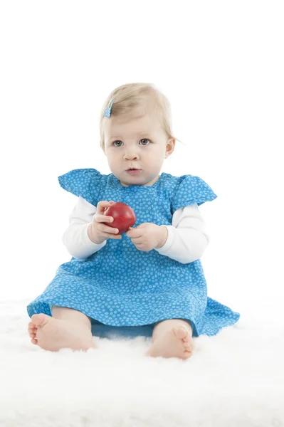 Babymeisje in blauwe jurk met apple — Stockfoto