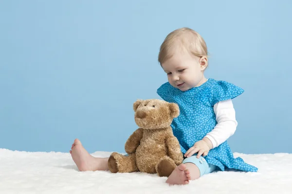 Little baby girl with teddy bear, on blue — Stock Photo, Image