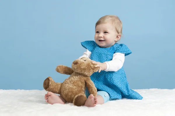 Little baby girl with teddy bear, on blue — ストック写真