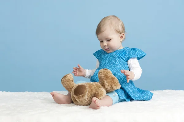Little baby girl with teddy bear, on blue — Stock Photo, Image