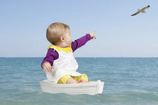 Лето: маленький ребенок в лодке на берегу океана — стоковое фото