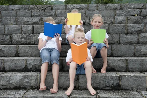 Summer holidays: children with a book seated outdoors on stairs — Stock Photo, Image