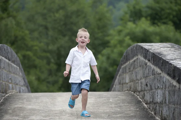 Summer time : little boy running on a bridge — Stock Photo, Image